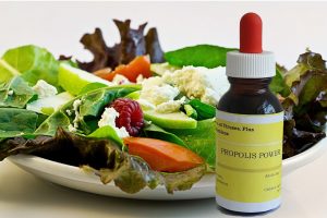 salad on plate with liquid propolis in bottle on right